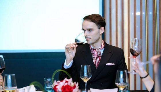 Trainer demonstrating wine tasting at a formal table